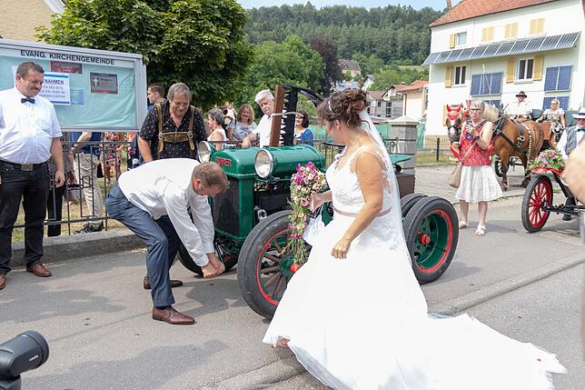 Benny zeigt beim Anwerfen eines Oldtimer-Traktors sein Können. Nadine feuert ihn an.