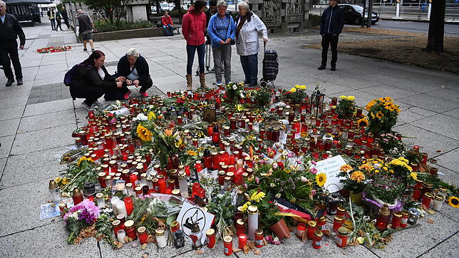 Passanten stehen am Tatort, an dem zahlreiche Blumen und Kerzen niedergelegt wurden. Am Sonntag war in Chemnitz ein 35 Jahre alter ...