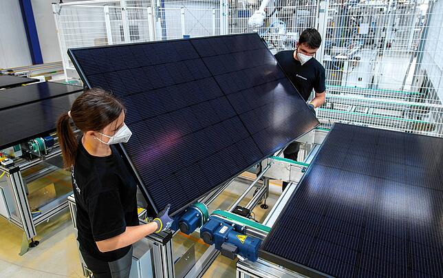 Zwei Mitarbeiter des Werks der Meyer Burger Technology AG in Freiberg begutachten der Endkontrolle einer Produktionslinie ein Solarmodul.