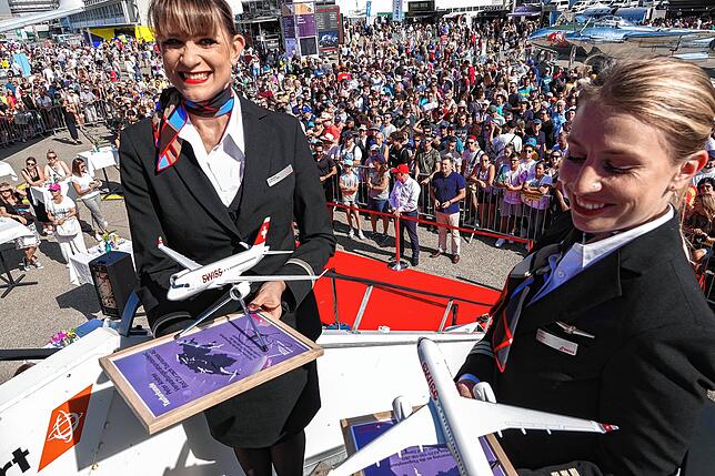 Zwei Flugbegleiterinnen stehen bei der Taufzeremonie vor großem Publikum.