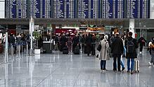 Passagiere stehen vor einer Anzeigetafel im Terminal 2 am Flughafen München. Wegen Drohnensichtungen sind am Flughafen in München am ...