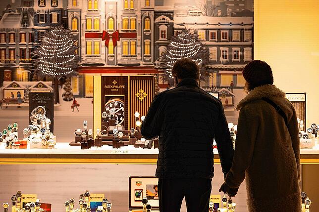 Passanten stehen in Frankfurt vor einem weihnachtlich dekorierten Schaufenster.