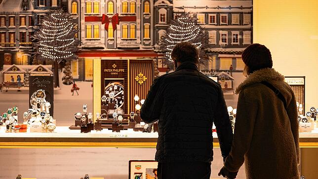 Passanten stehen in Frankfurt vor einem weihnachtlich dekorierten Schaufenster.