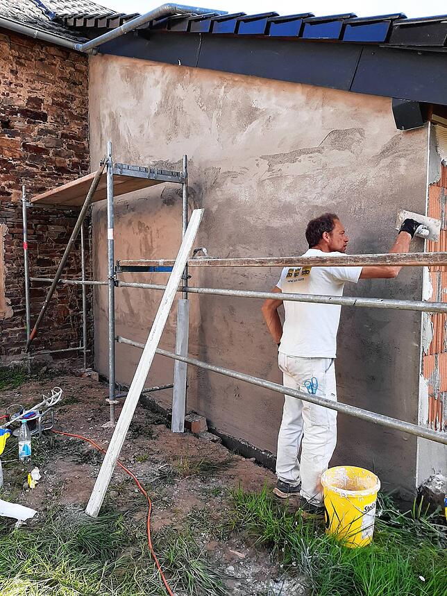 Ein Gipsermeister, der Mitglied der Feuerwehr Hänner ist, verputze die neu aufgebaute Außenwand des Hauses, die vom Hochwasser völlig ...