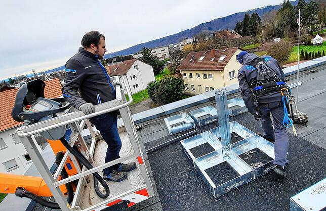 Marvin Rüther (links) bringt seinem Kollegen Marco Strauß per Hubsteiger das Material aufs Dach.