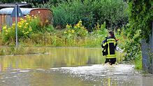 Eine Feuerwehrfrau watet durch Wassermassen in Markdorf.