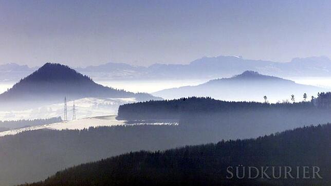 Während am Bodensee dichter Nebel herrscht, liegen die Spitzen der Hegauvulkane im Sonnenlicht. Im Hintergrund sind die Schweizer Alpen ...