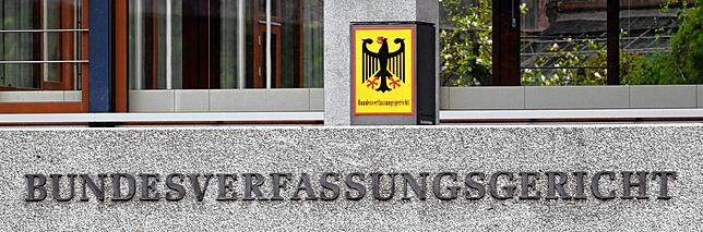 Außenaufnahme des Bundesverfassungsgerichts mit einem Hinweisschild auf dem der Bundesadler und das Wort Bundesverfassungsgericht ...