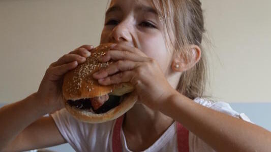 Olivia zwängt ihren Riesen-Burger in den Mund.