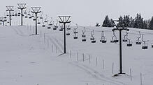 Ein Lift steht auf dem Feldberg im Schwarzwald über einem schneebedeckten Hang. Das Ski-Vergnügen kann starten.