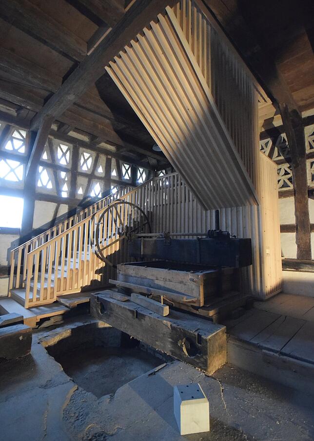 Die neue Treppe schlingt sich um eine historische Mostpresse. Die Treppe besteht aus Hölzern, wie sie überall in der Torkel zu finden ...