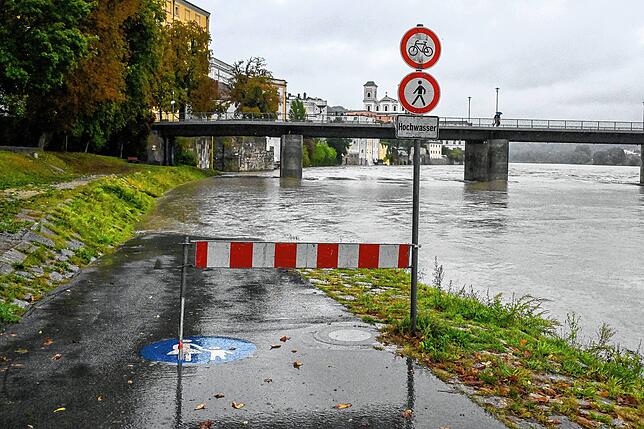 Bayern, Passau: Eine Absperrung steht am überschwemmten Innufer. Auch wenn in Bayern der meiste Regen des Wochenendes wohl schon ...