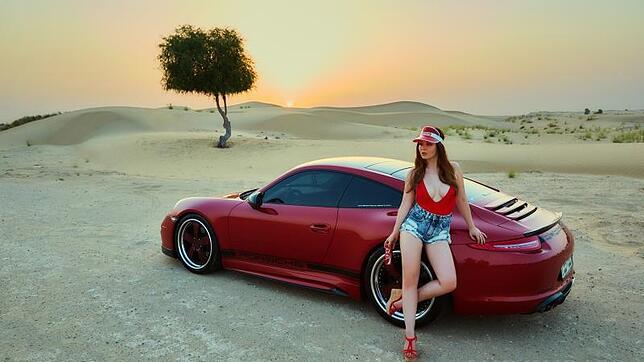 Das Titelbild des Miss Tuning Kalenders 2017 zeigt einen Sonnenuntergang in der Wüste Dubais, Julia Oemler steht vor einem 911er Porsche ...