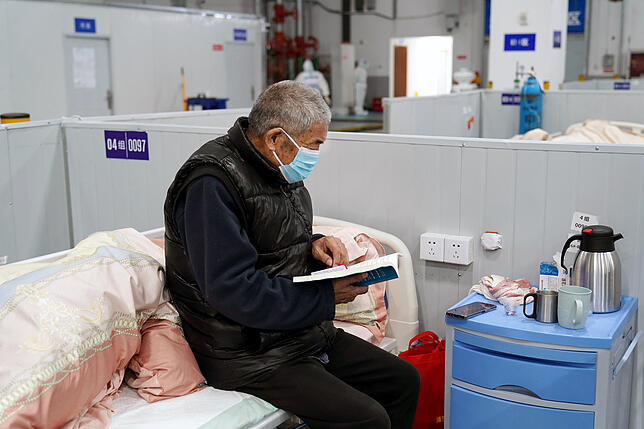 Ein älterer Mann liest ein Buch im Behelfskrankenhaus in Lingang. Hier werden Patienten mit mäßigen Symptomen und Betroffene über 80 ...