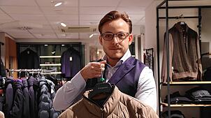 Maximilian Wichert, Assistent der Geschäftsführung beim Modehaus Munding in Überlingen, zeigt eine Übergangsjacke.