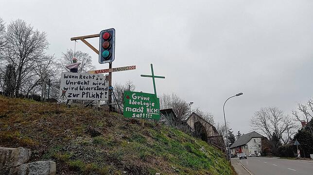 Ein Ampel-Galgen mit einer daran aufgeknüpften Puppe, ein grünes Holzkreuz und Protestplakate stehen in Rhina an der L151.