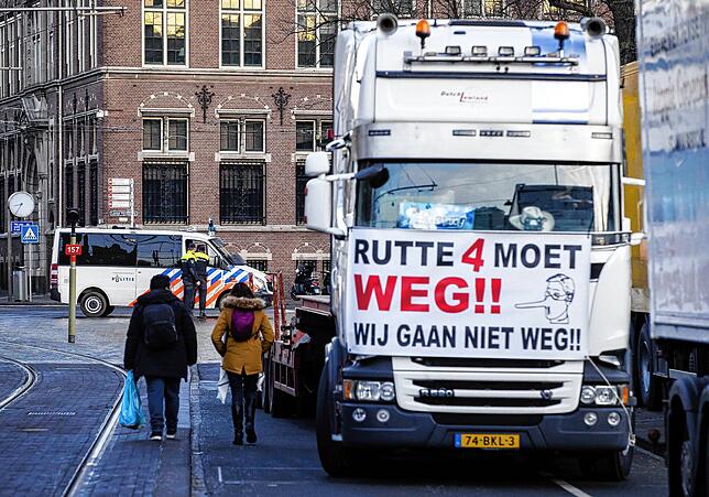 Ein LKW steht auf einer Straße, während im Hintergrund Polizisten eine Kreuzung blockieren. Bei einer Demonstration, nach Vorbild ...