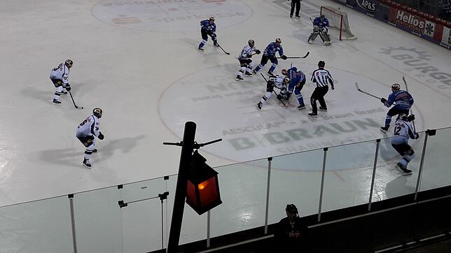 Symbolträchtig: Während die Profis aus München und Schwenningen auf dem Eis um den Puck kämpfen, leuchtet am Spielfeldrand eine rote ...