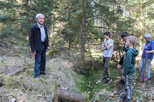 Da, wo einst der Mühlenweier war, ist jetzt Wald. Emil Tritschler erklärt, wo Zu- und Ablauf waren. Auch die jungen Hubertshofener hören ...