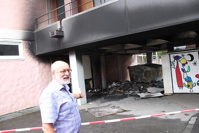 Rektor Gottbert Hogg zeigt auf den verrußten Container, von dem aus der Brand auf die Eichendorff-Realschule übergriff. Bild: Albert ...