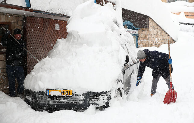 Österreich, Filzmoos: Zwei Männer befreien im Salzburger Land ein Auto vom Schnee.