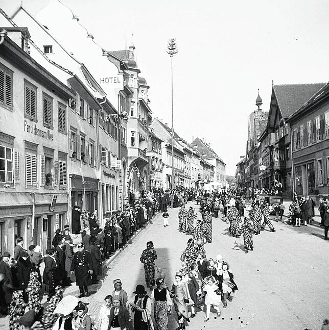 Ein Umzug in der Hauptstraße. Im Hintergrund steht der Narrenbaum.