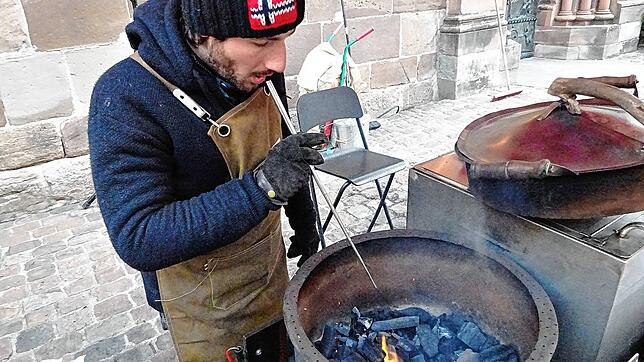 Jerome Hummel an seinem Maronenstand: Er steht direkt auf dem Kopfsteinpflaster, das tiefgefroren ist. Und bläst hier mithilfe eines ...