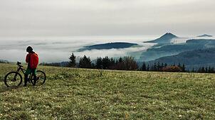 Der Hegau im Nebel: Wie in Watte gepackt schaue die Spitzen einzelner Hegau-Vulkane aus der dichten Wolkendecke. Ein Mountainbiker hat ...