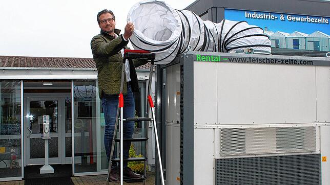 Geschäftsführer Hans Fetscher steht auf einer Klappleiter neben einem Be- und Entlüftungssystem, das beispielsweise für häufig ...
