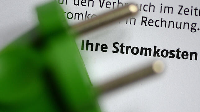 Ein grüner Stromstecker liegt auf einer Stromrechnung.