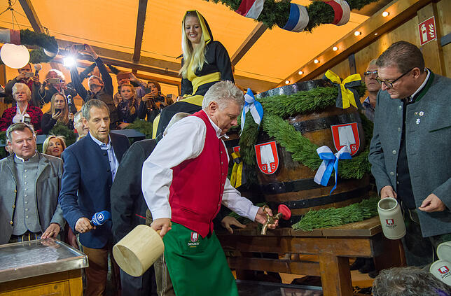 Der Münchner Oberbürgermeister Dieter Reiter (M, SPD) zapft das erste Fass Bier mit zwei Schägen an.