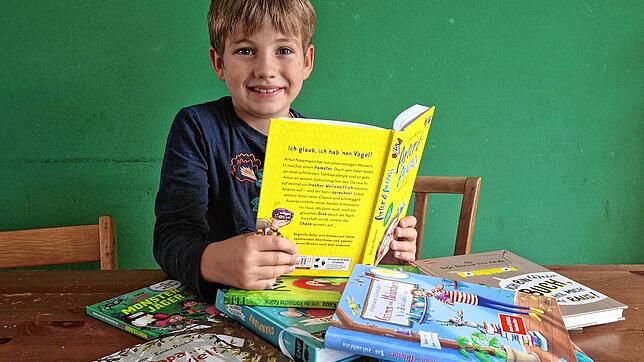 Vor David liegen zehn Kinderbücher, die alle für den Deutschen Kinderbuchpreis nominiert sind. David bestimmt mit 31 anderen Kindern, ...