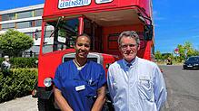 Hubert Kimmig und Krankenschwester Rebecca Katz vor dem Londoner Doppeldeckerbus der Gesundheitsinitiative „Herzenssache Lebenszeit“. ...
