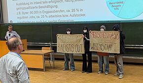 Vermummte protestieren in der Uni Konstanz bei der Auftaktvorlesung des Studium Generale zum Thema „Migration steuern“ mit Plakaten und ...