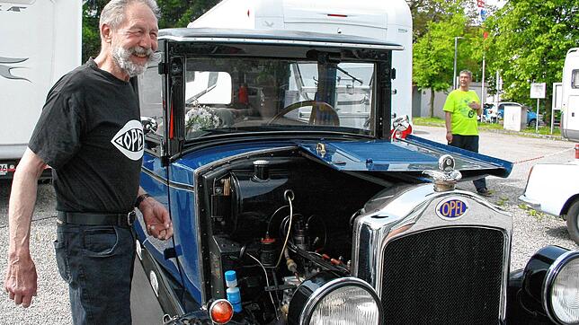 Wer sein Auto liebt, der schraubt. Ein stolzer Oldtimer-Besitzer auf dem Auplatz. Die historischen, schmucken Fahrzeuge sind ...