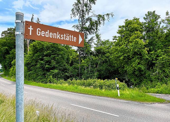 Ein kleines Schild am Straßenrand verweist auf die unauffällige Gedenkstätte.