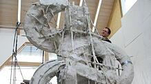 Insgesamt neun Meter hoch soll die Skulptur von Peter Lenk werden. Hier verspachtelt sein Helfer, Kunstgießer Johannes Traub, die ...