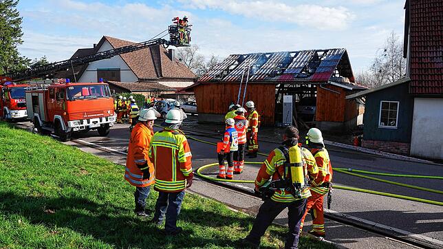 Feuerwehrleute und Feuerwehrfahrzeuge vor der Garage, die am Freitag gebrannt hatte.