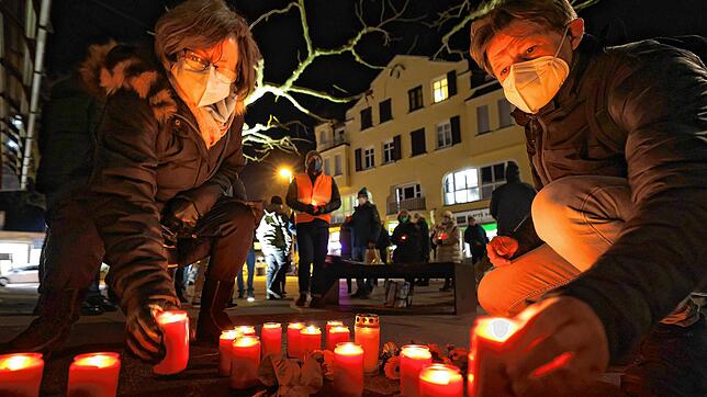 Zwei Teilnehmer der Holocoust-Gedenkveranstaltung stellen ein Kerzenlicht am Gurs-Gedenkstein auf dem Seetorplatz auf.