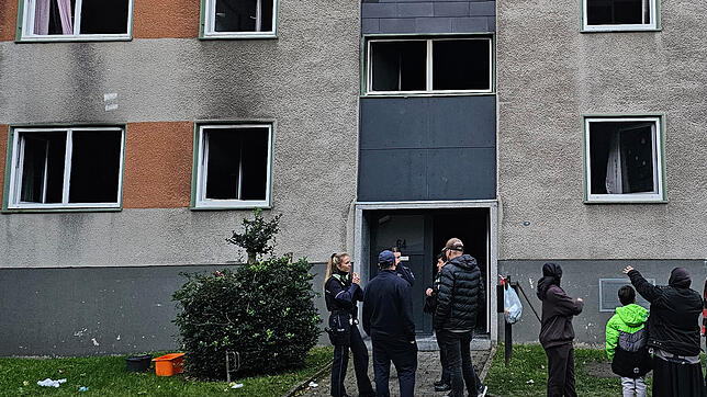 Polizisten stehen nach einem Brend in Essen mit Bewohnern vor einem Wohnhaus. In Essen sind bei mehreren Feuern mehrere Menschen ...