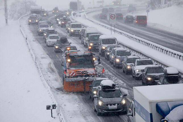 Bayern, Siegsdorf: Ein Fahrzeug vom Winterdienst steht im Stau auf der verschneiten Autobahn A8 bei Siegsdorf, wo Bäume am Straßenrand ...