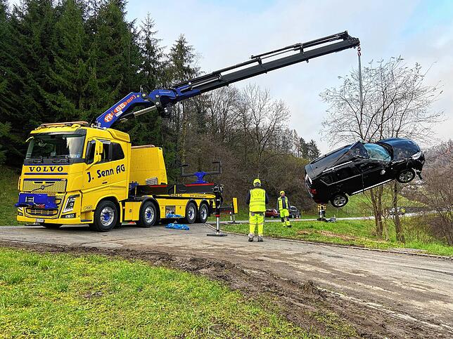 Ein Kranfahrzeug hebt das Auto aus dem Bach.