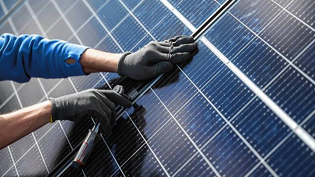 Ein Mann montiert Photovoltaikmodule auf dem Dach eines Wohnhauses. Mehr als 3 Millionen Solaranlagen gibt es bereits in Deutschland. ...