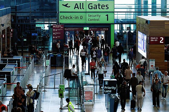 Passagiere sind in einem Terminal am Berliner Flughafen BER unterwegs.