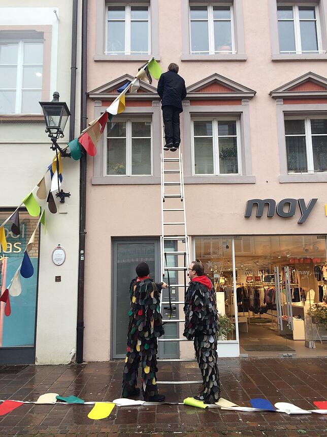 Mitglieder der Narro-Zunft hängen die abgerissenen Fasnachtsgirlanden ab.