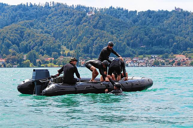 Vier Soldaten befinden sich im Wasser und müssen in der Übung gerettet werden. Sie helfen sich auch gegenseitig ins Boot.