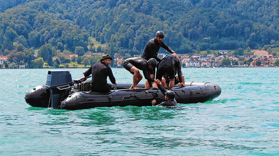 Vier Soldaten befinden sich im Wasser und müssen in der Übung gerettet werden. Sie helfen sich auch gegenseitig ins Boot.