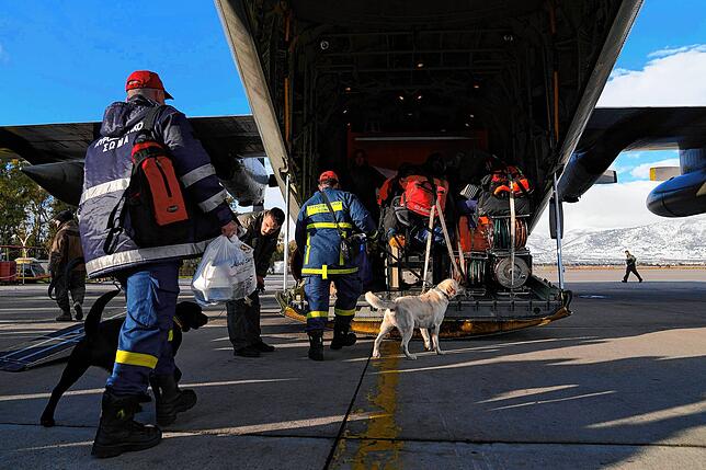 Griechische Feuerwehrleute mit Hunden besteigen ein Militärflugzeug auf dem Luftwaffenstützpunkt Elefsina im Westen von Athen. Sie sind ...