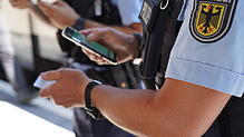 (Symbolbild) Bundespolizisten kontrollieren mit einer App die Personalien einer Person. Am Bahnhof Singen entdecken die Beamten am ...