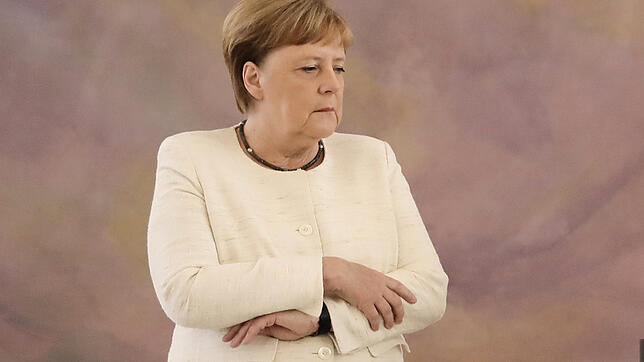 Wieder ein Zitteranfall, diesmal in Schloss Bellevue. Merkel verschränkt die Arme vor dem Bauch. Will sie das Zittern verbergen?